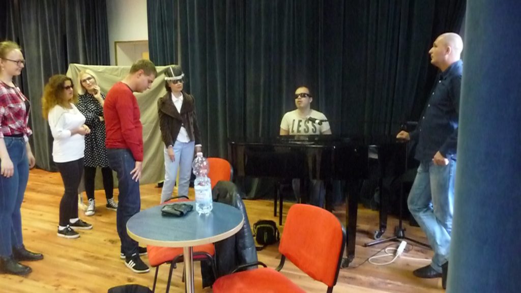 Uczestnicy warsztatów zgromadzeni wokół fortepianu, a gra im Grzegorz Dowgiałło i udziela rad Łukasz Baruch  