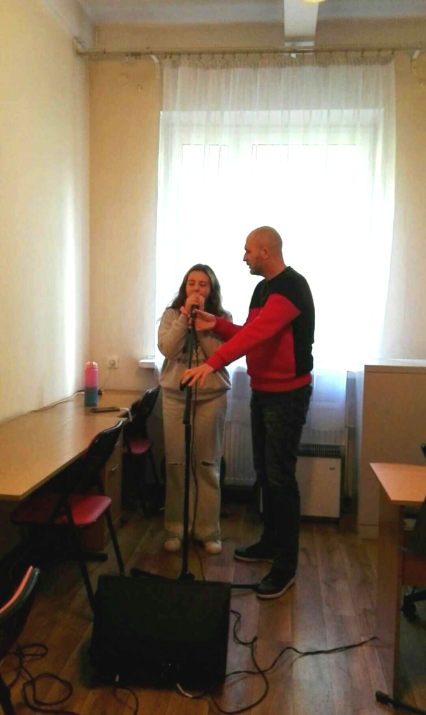 Łukasz Baruch i uczestniczka warsztatów - instruktor udziela jej wskazówek jak trzymać mikrofon. 