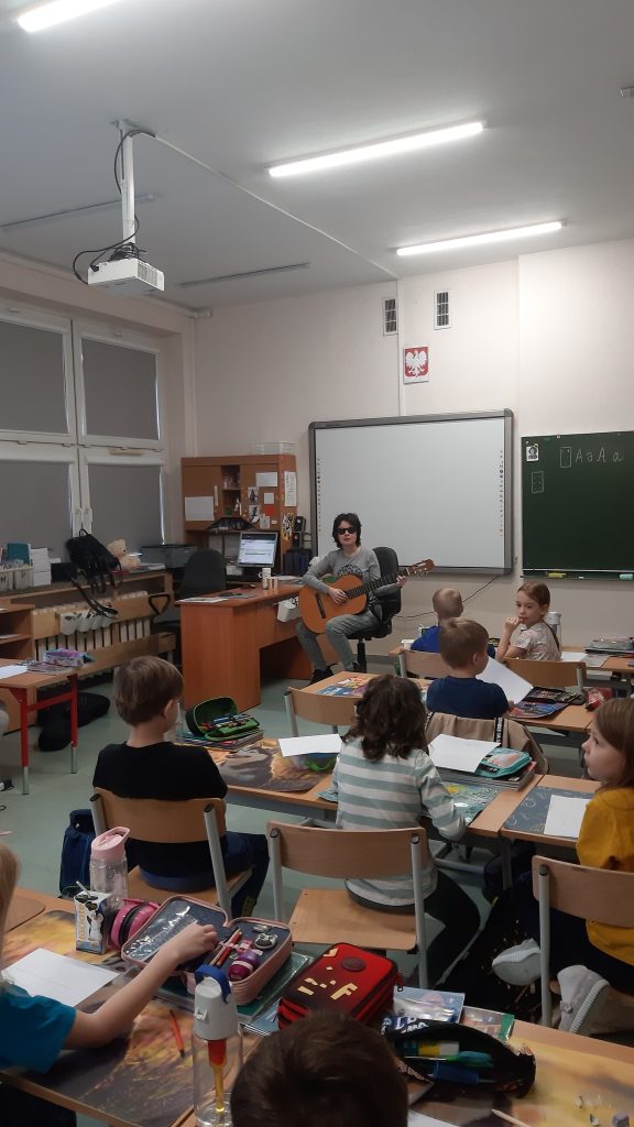 Uczniowie w ławkach, Kasia gra na gitarze.