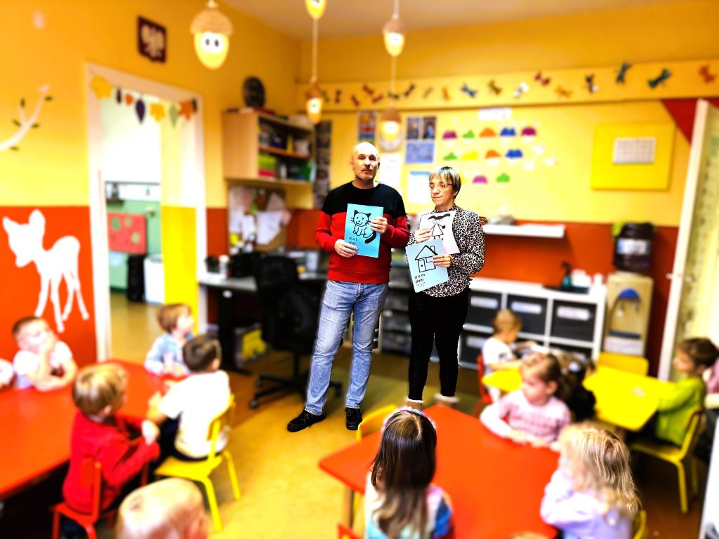 Łukasz i Justyna pokazują dzieciom obrazki, które będą wyklejać.