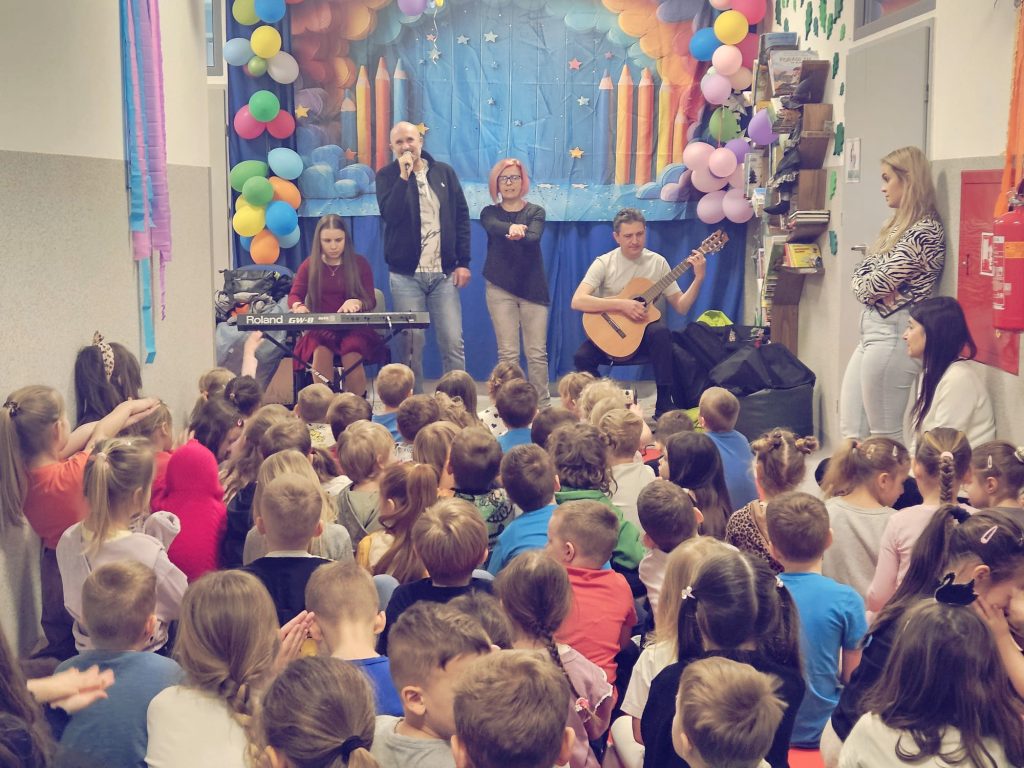 Warsztaty: Rita gra na klawiszu, Łukasz śpiewa, Karolina klaszcze, Żenia gra na gitarze, przed wokalistami publiczność - dzieci i nauczycielki z przedszkola. 